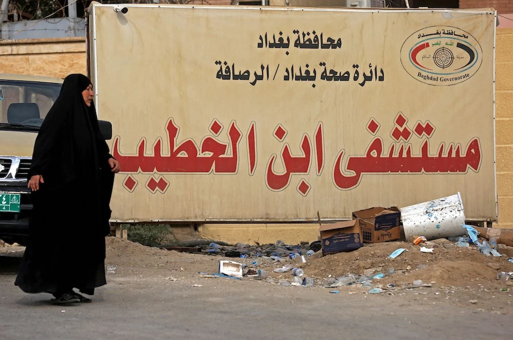 An Iraqi woman walks past a billboard bearing the name of Ibn Al-Khatib Hospital in Baghdad, on April 25, 2021, after a fire erupted in the medical facility reserved for the most severe COVID-19 cases. (AFP)