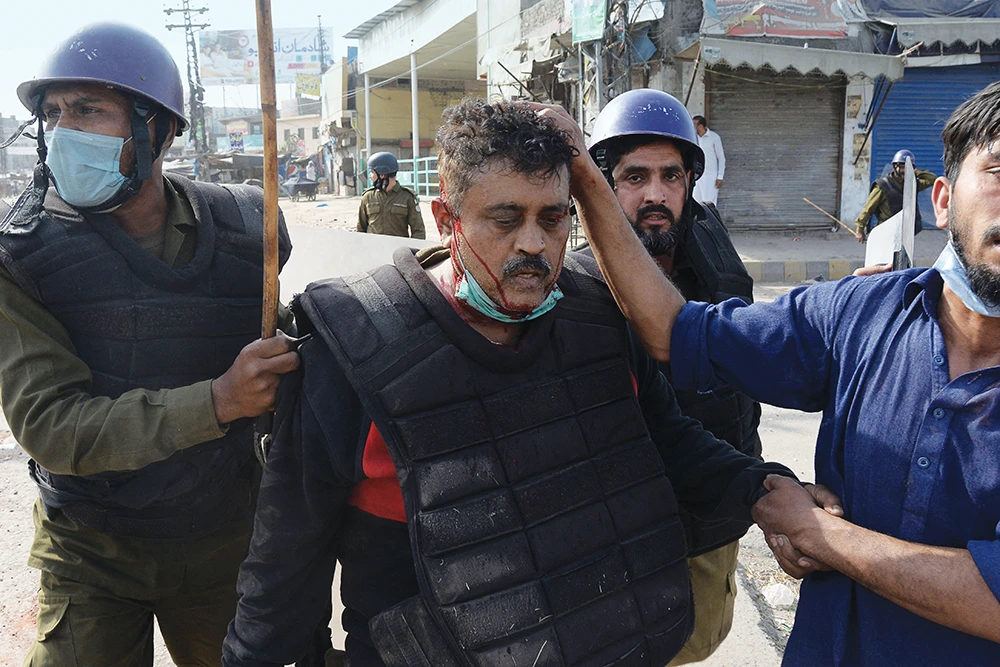 Policemen help an injured colleague during a clash with supporters of Tehreek-e-Labbaik Pakistan party after a demonstration against the arrest of their leader. (Getty Images)