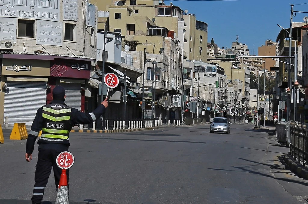 A policeman holds a stop sign in an almost deserted avenue in the Jordanian capital Amman, during a lockdown due to the coronavirus panemic, on Feb. 26, 2021. (File/AFP)