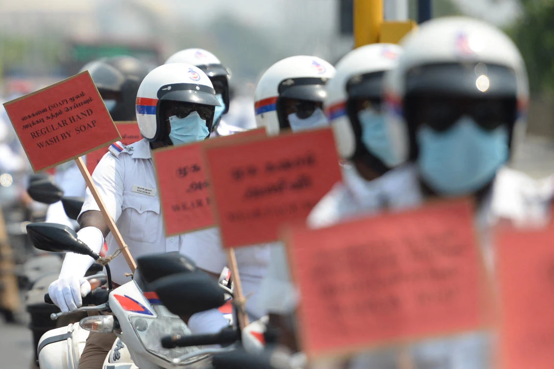 Police personnel riding on motorbikes hold placards during a COVID-19 coronavirus awareness rally in Chennai. (AFP)