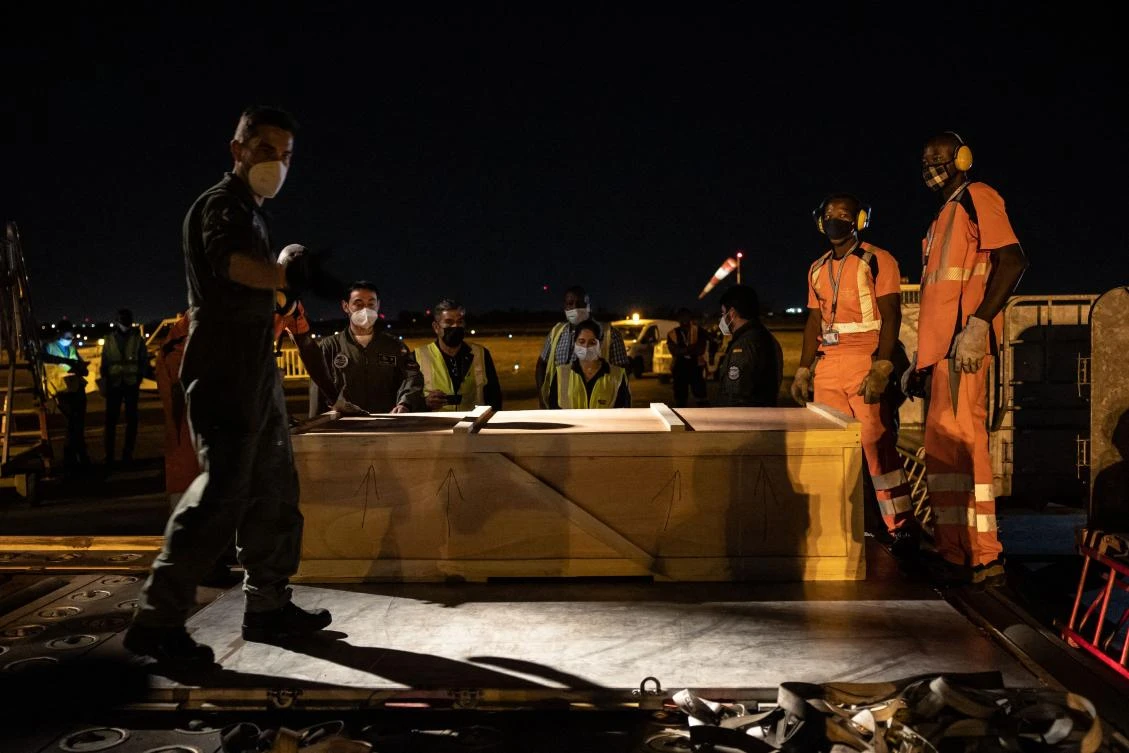 Ouagadougou’s airport staff carries the coffin of one of the three Europeans killed in an attack in Eastern Burkina to the Spanish military plane that is flying their remains back to Spain, at Ouagadougou airport on April 30, 2021. (AFP)