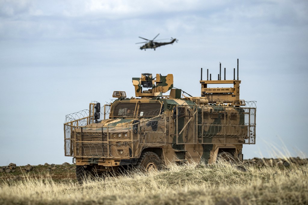 A Russian Mil Mi-24 Hind helicopter gunship flies above a Turkish military vehicle in Syria’s northeastern Hasakeh province close to the Turkish border, on February 4, 2021. (AFP)