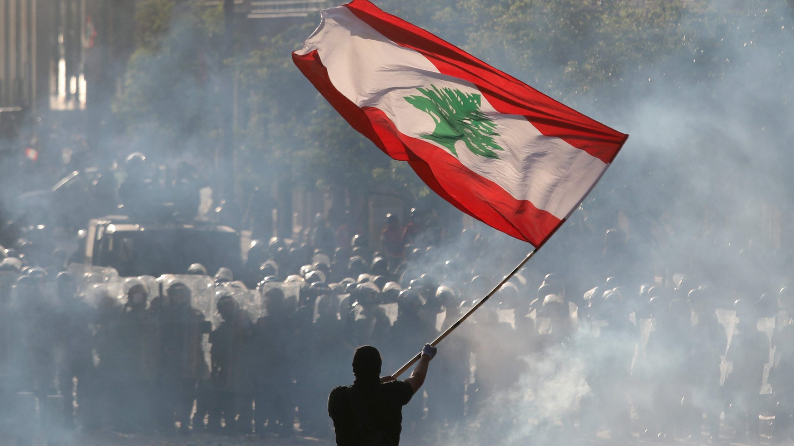 An anti-government protester waves a Lebanese flag during clashes with security forces in Beirut, Aug. 8, 2020. (Reuters)