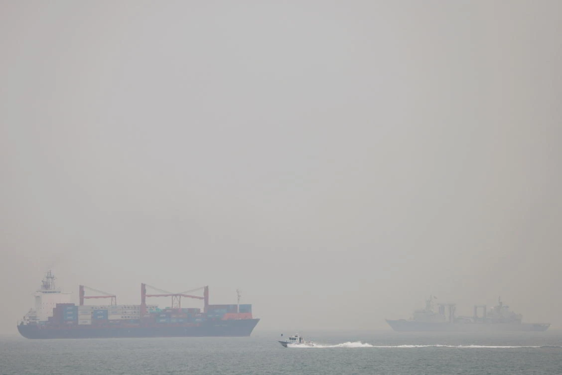 Above, a container vessel and a People’s Liberation Army Navy vessel are seen in fog off the coast of Qingdao, Shandong province in China on April 29, 2021. (Reuters)