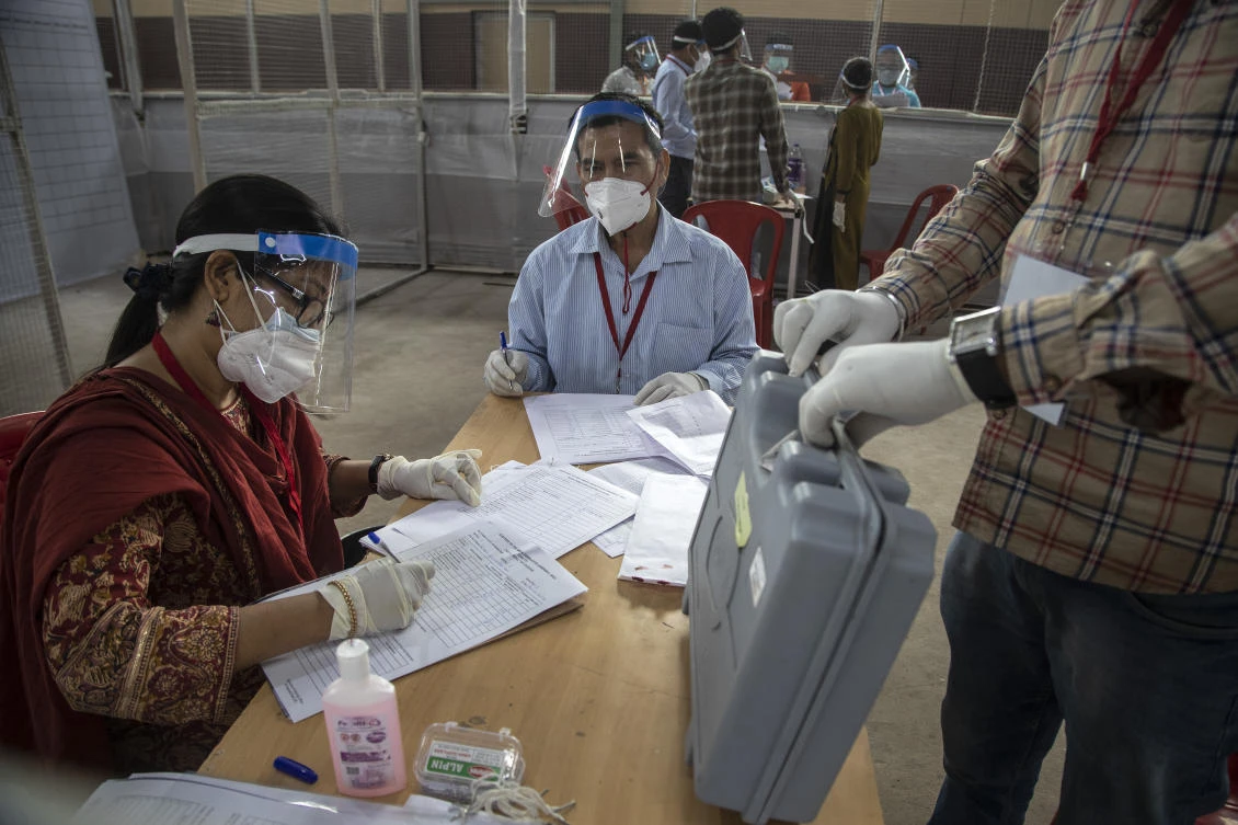 Election officials sit wearing masks and face shields during the counting of votes of Assam state assembly election in Gauhati, India, Sunday, May 2, 2021. (AP)
