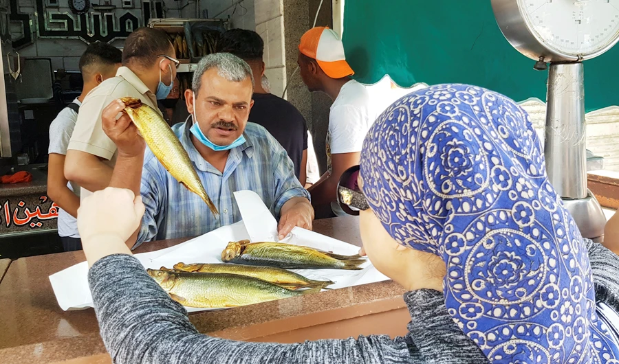 An Egyptian woman buys smoked herring known as "Renga", ahead of the traditional spring holiday of 'Shem al-Neseem' during the holy fasting month of Ramadan, in Cairo, Egypt, May 2, 2021. (REUTERS)