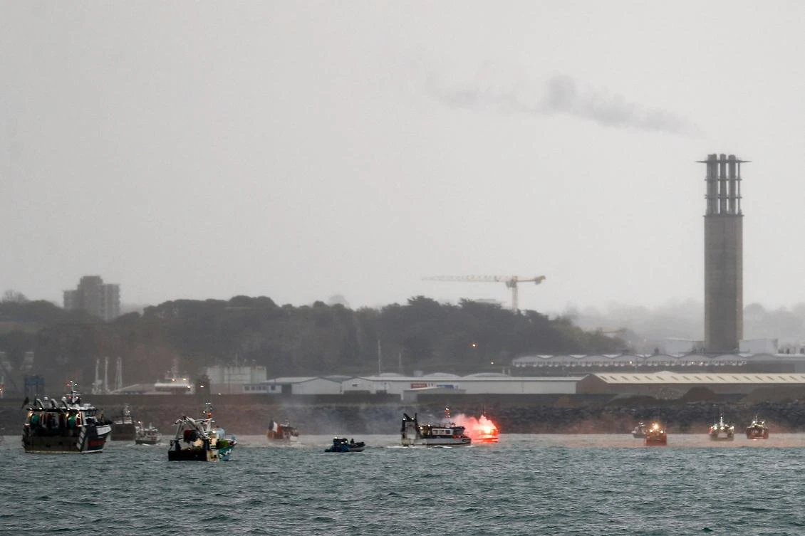 A flare is lit as French fishing boats protest in front of the port of Saint Helier off the British island of Jersey to draw attention to what they see as unfair restrictions on their ability to fish in UK waters after Brexit, on May 6, 2021. (AFP)