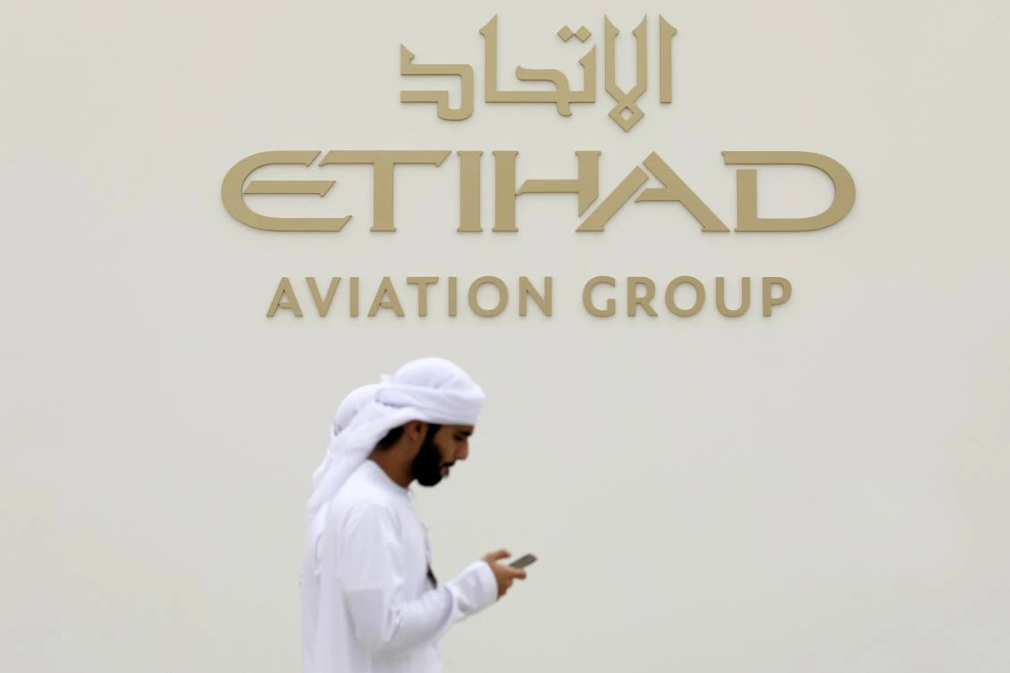 A visitor walks past the Etihad Aviation Group logo on display during the fifth day of Dubai Air Show in Dubai. (Reuters)