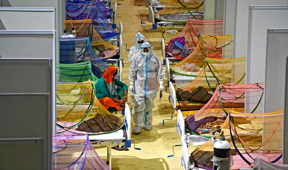 Health workers wearing personal protective equipment (PPE) suits attend Covid-19 coronavirus patients inside a centre of the Commonwealth Games (CWG) village temporarily converted into a Covid care facility, in New Delhi on May 2, 2021. (AFP)