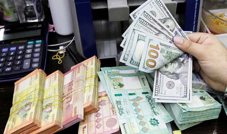 A man counts U.S. dollar banknotes next to Lebanese pounds at a currency exchange shop in Beirut, Lebanon April 24, 2020. (REUTERS)