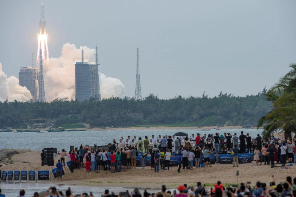 People watch from a beach as the Long March-5B Y2 rocket, carrying the core module of China's space station Tianhe, takes off from Wenchang Space Launch Center in Hainan province on April 29, 2021. (China Daily via REUTERS)