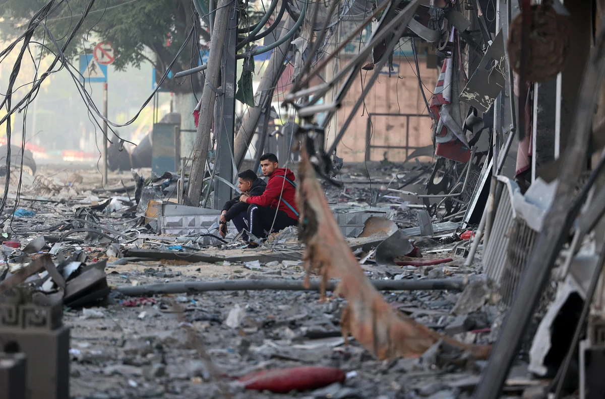 Palestinian men sit amidst debris near the al-Sharouk tower, which housed the bureau of the Al-Aqsa television channel in the Hamas-controlled Gaza Strip, after it was destroyed by an Israeli air strike, in Gaza City, on May 13, 2021. (AFP)