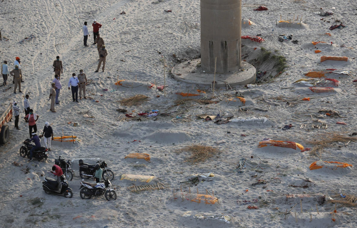 Above, policemen stand next to the bodies buried in shallow graves on the banks of Ganges river in Prayagraj. India’s coronavirus death toll now stands at 270,000. (AP)