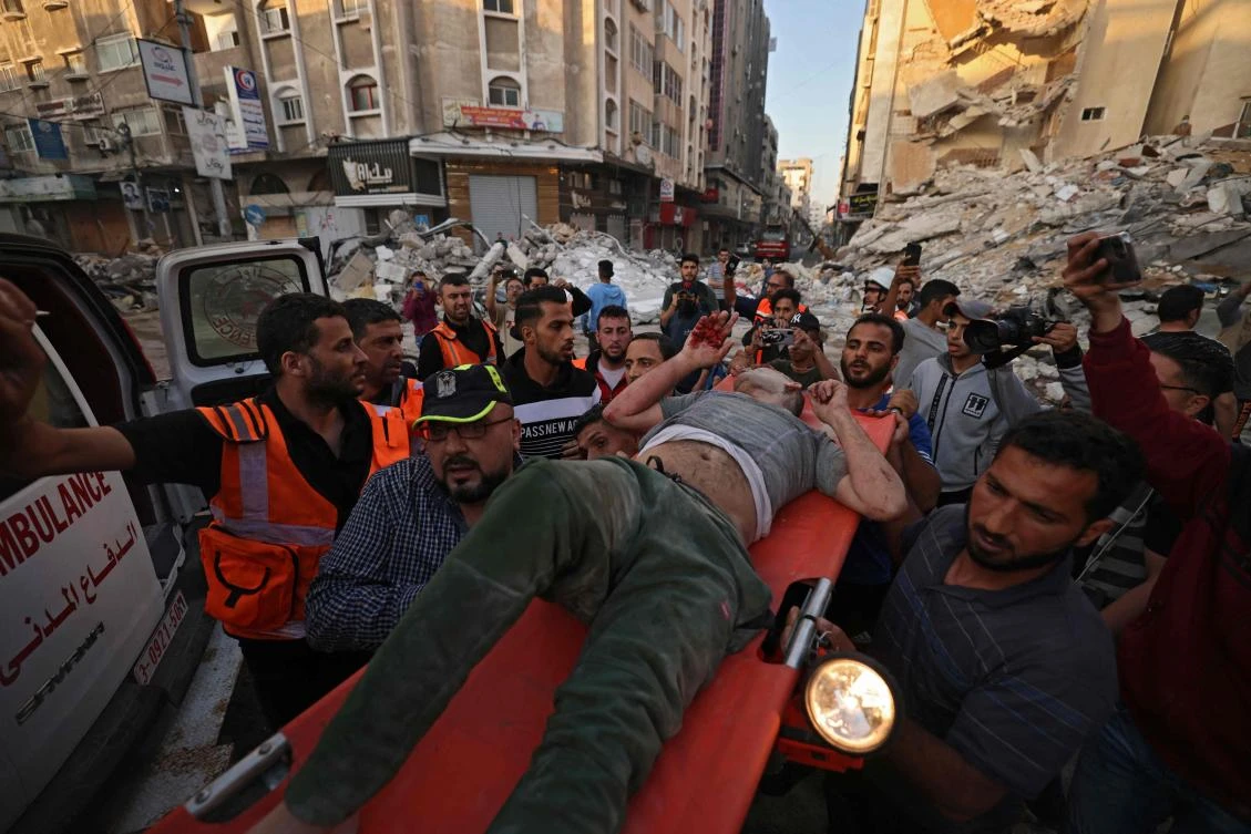 Palestinians carry one of survivors from under the rubble of a building after it was hit by Israeli strikes in Gaza City on May 16, 2021. (AFP)