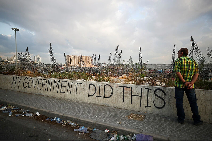 A man stands next to graffiti on Aug. 11, 2020, outside Beirut’s port, in the aftermath of the massive explosion that damaged much of Lebanon’s capital. (Reuters)