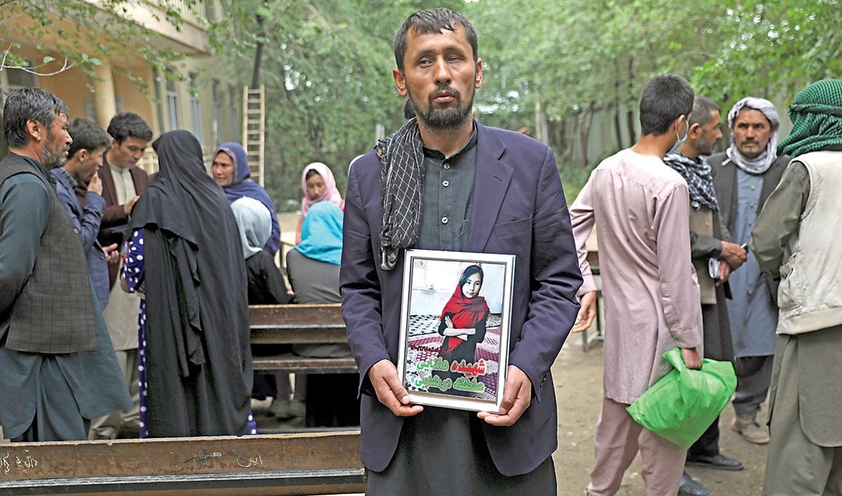 A man holds a photograph of his daughter who was among those killed in the May 8 bombing of a girls school, after a demonstration in Kabul on Sunday. (AP)