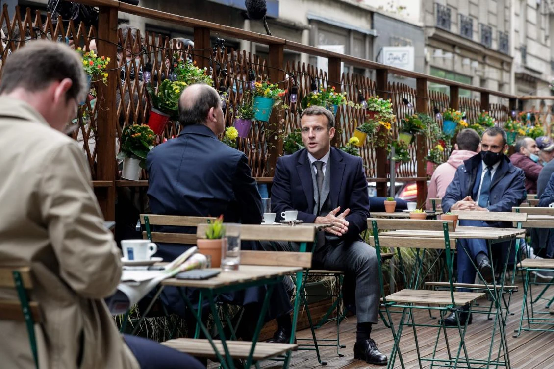 French President and French Prime Minister at a cafe terrace in Paris on Wednesday as restaurants and bar terraces reopen today at 50-percent capacity while curfew will be pushed to 9:00 pm. (AFP)