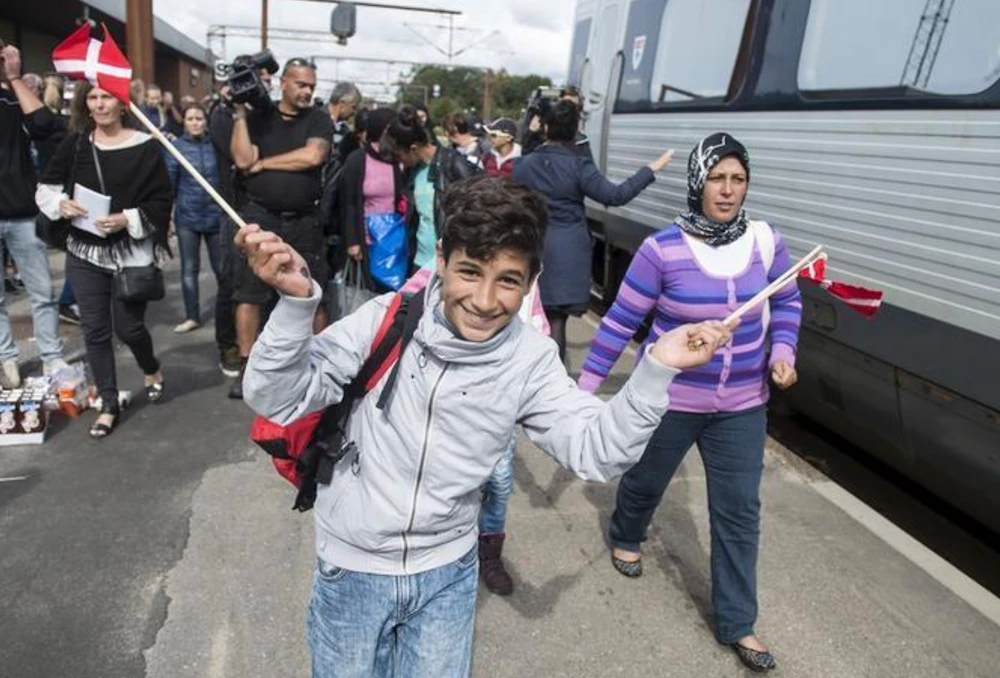 A boy waves Danish flags as he joins fellow migrants, mainly from Syria, on Padborg station. Denmark has taken in around 32,000 Syrians since the start of their country’s conflict. (Reuters/File Photo)