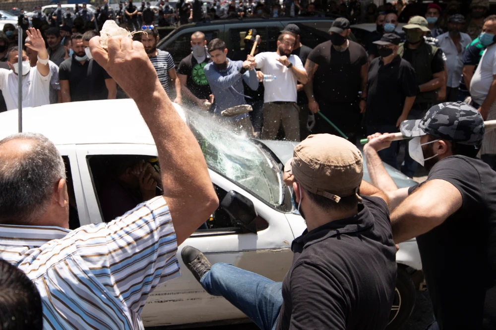 Members of the Christian rightwing Lebanese Forces group attack a car carrying Syrian voters before heading to the Syrian embassy to vote, in the town of Zouk Mosbeh, north of Beirut, Lebanon, Thursday, May 20, 2021. (AP)