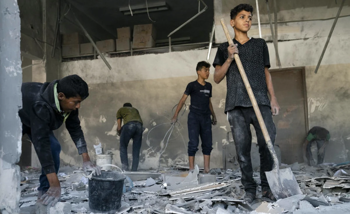 Children salvage debris from a building that was severely damaged by an air-strike prior to a cease-fire reached after an 11-day war between Gaza's Hamas rulers and Israel, Sunday, May 23, 2021, in Beit Lahia, the Gaza Strip. (AP)