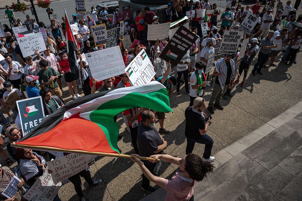 A woman waves a Palestinian flag during a pro-Palestine protest on the steps of City Hall on May 23, 2021 in Louisville, Kentucky. (AFP)