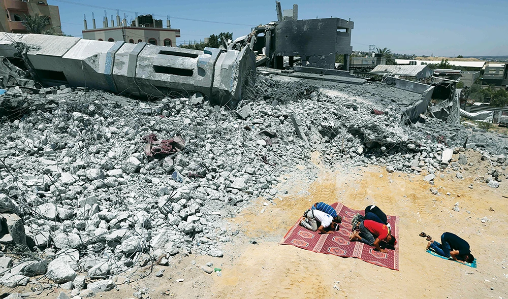 Men in Gaza Strip, on Thursday, pray near the rubble of a mosque, destroyed during Israeli airstrikes that left 248 dead in the besieged enclave. (AP)