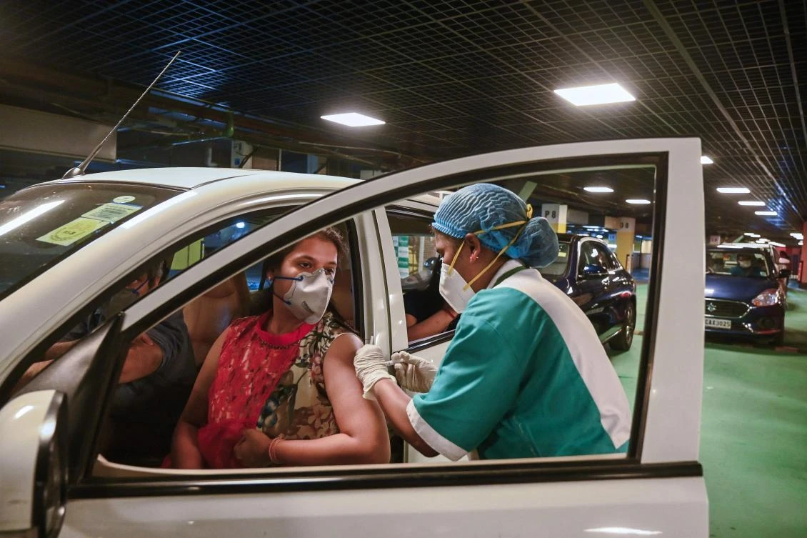 A health worker inoculates a woman with a dose of the Covaxin vaccine against coronavirus at a mall in New Delhi on May 28, 2021. (AFP)