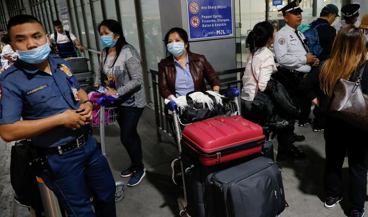 Overseas Filipino Workers (OFW) wearing protective masks standby outside the Ninoy Aquino International Airport in Pasay City, Metro Manila, Philippines. (Reuters)