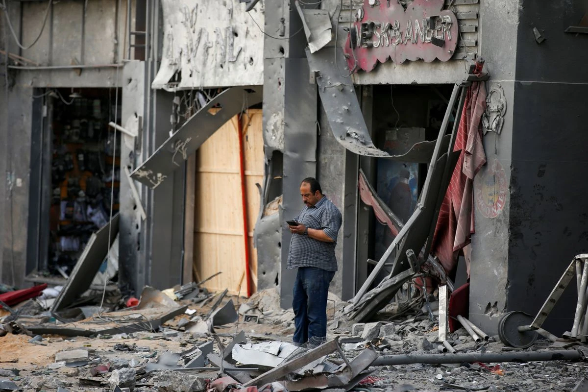 A Palestinian man stands outside damaged shops in the aftermath of Israeli air strikes, on the first day of Eid al-Fitr, Gaza City, May 13, 2021. (Reuters)