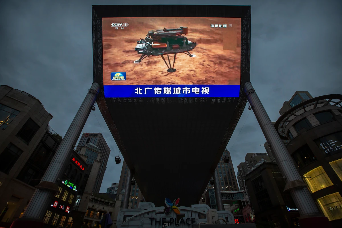 A news report about China’s successful landing of a probe on Mars is shown on a large video screen in a Beijing shopping mall-AP