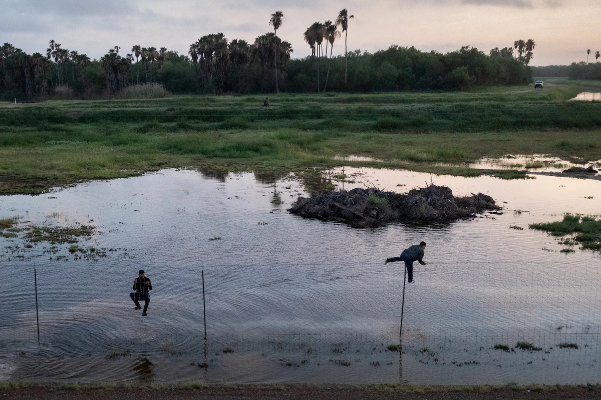 Migrants jump a fence as they run towards Mexico while being chased by US border patrol after crossing the Rio Grande river into the US from Mexico. (Reuters)