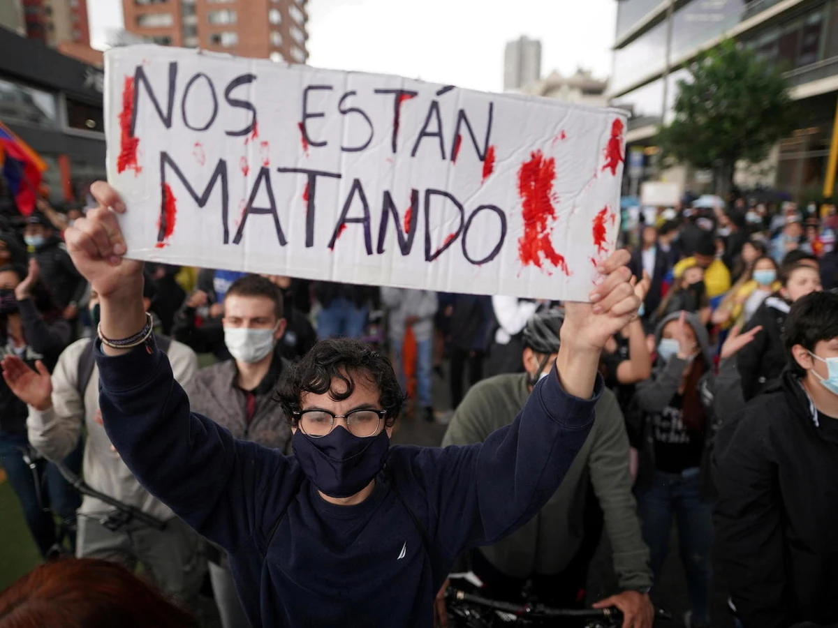 A demonstrator holds a sign reading They Are Killing Us during a protest against poverty and police violence, Bogota, May 4, 2021. (Reuters)