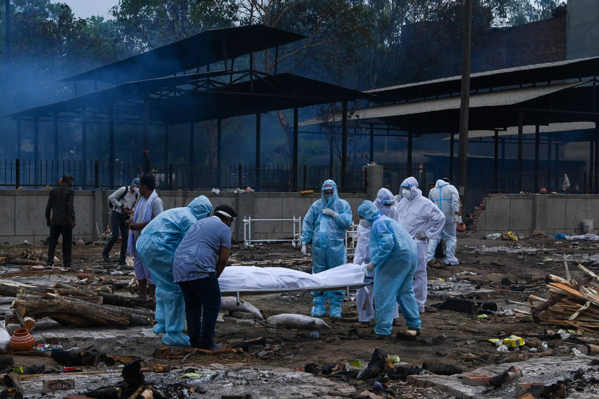 Relatives in personal protective equipment (PPE) suits carry the body of a person who died due to the Covid-19 coronavirus, at a cremation ground in New Delhi, India, on May 6, 2021. (AFP / Prakash Singh)