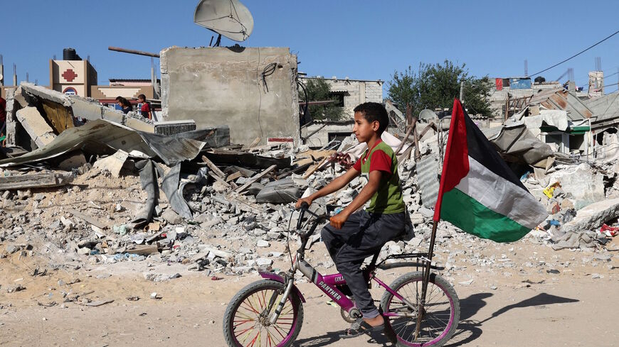 A Palestinian boy rides his bicycle in front of the ruins of a building destroyed by Israeli airstrikes in Rafah, southern Gaza Strip, May 26, 2021. (AFP )