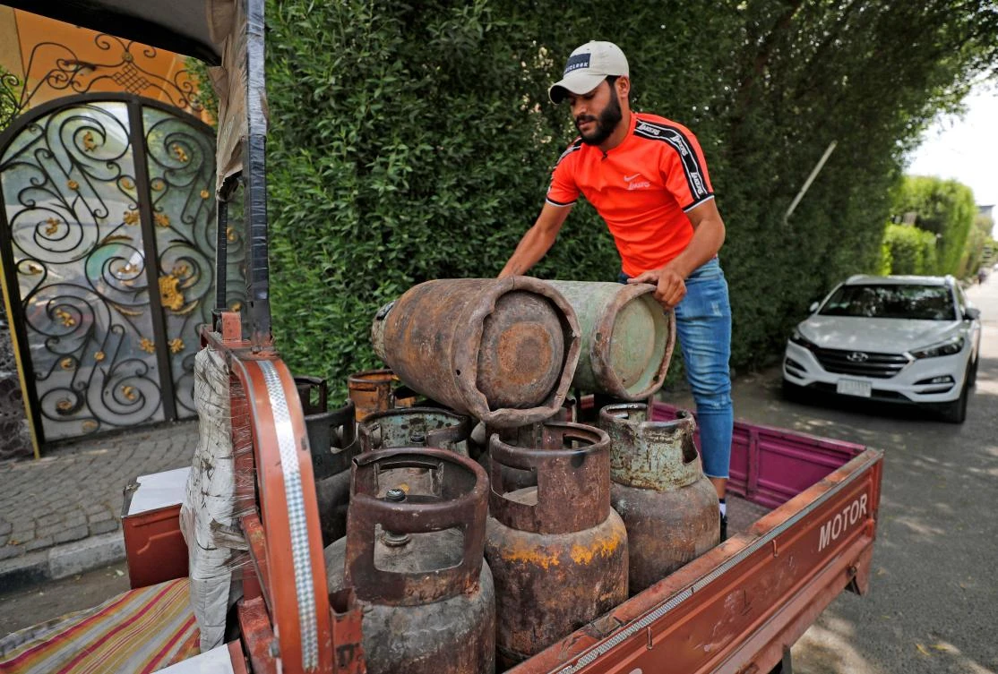 Deliveryman Mountazar Abbas unloads gas bottles from his loaded rickshaw in the Karrada district of Iraq's capital Baghdad. (AFP)