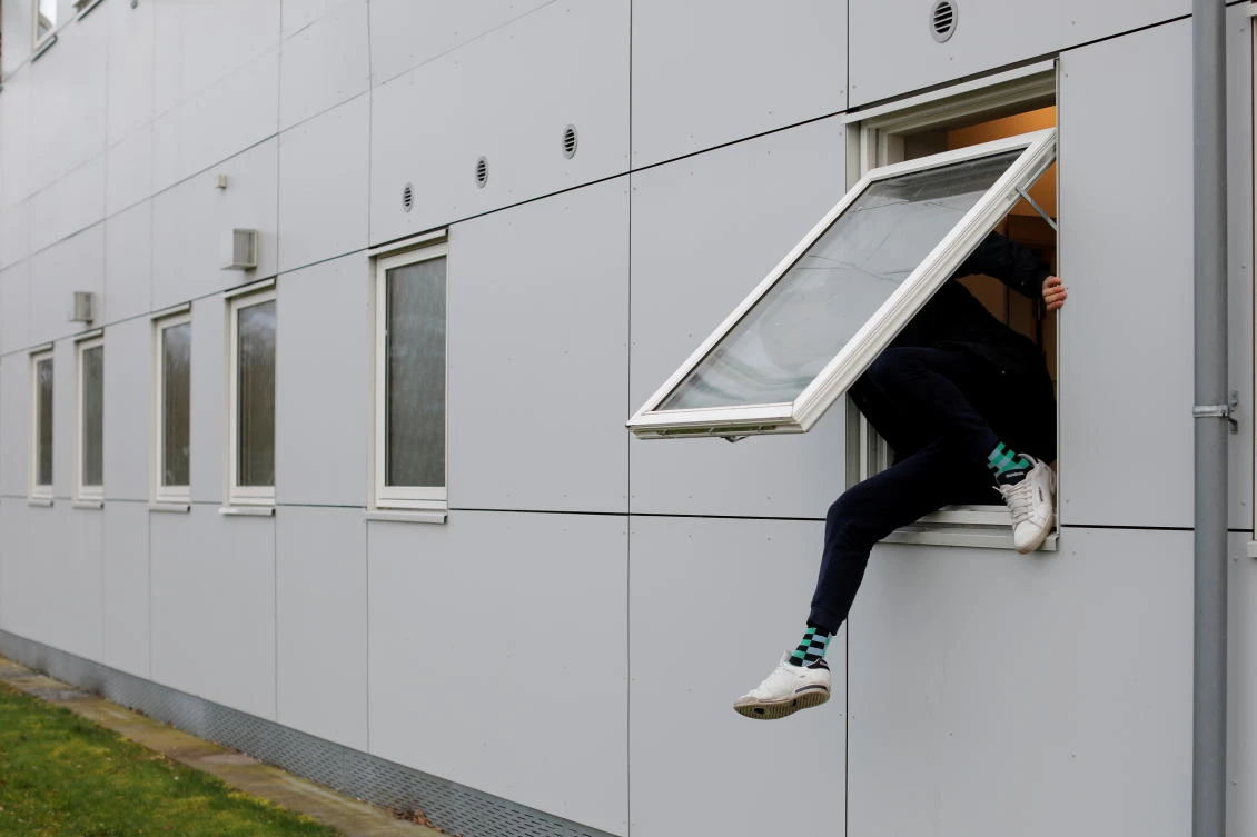 A resident climbs through a window at Kaershovedgaard, a former prison and now a departure center for rejected asylum seekers in Jutland, Denmark, March 26, 2019. (Reuters)