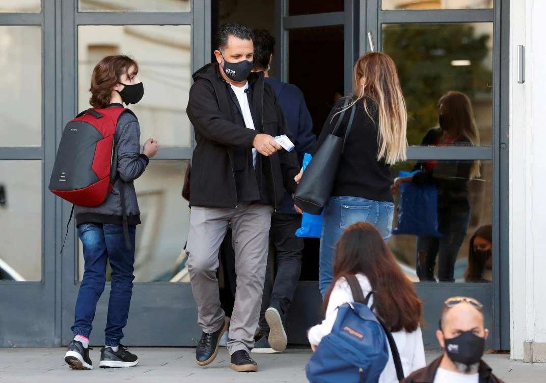 An employee checks a woman’s temperature at a school’s entrance, amid a rise in COVID-19 cases, in Buenos Aires. (Reuters)