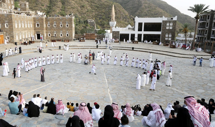 Tourists watch Saudi men perform a traditional folk dance at the cultural village of Rijal Almaa in the outskirts of Abha, Saudi Arabia July 17, 2020. (REUTERS)