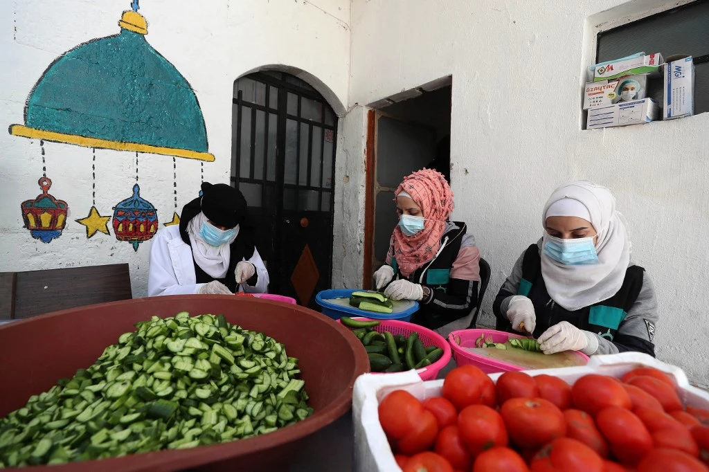 Syrian women helping out with “Hathi Hayati” volunteering group prepare meals to distribute to families in displacement camps for in Syria’s Idlib on April 24, 2021. (File/AFP)