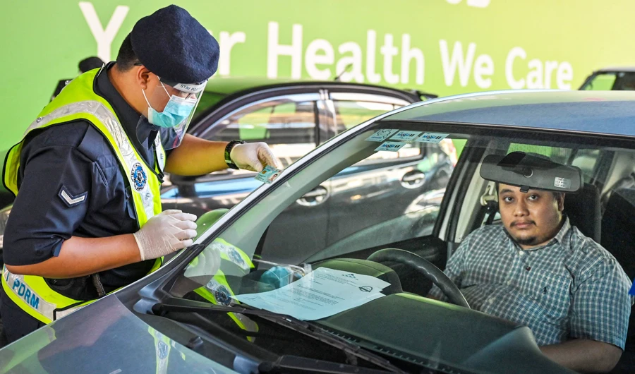 A policeman inspects the travel documents of a motorist at a roadblock during the nationwide lockdown, amid fears over the spread of the Covid-19 coronavirus, in Kuala Lumpur on June 1, 2021. (AFP)