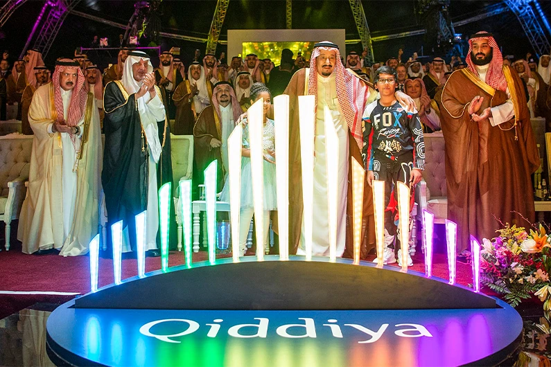 A handout picture provided by the Saudi Royal Palace on April 28, 2018, shows Saudi King Salman bin Abdulaziz (C-R) and his son, Crown Prince Mohammed bin Salman (R), embracing two children while standing behind the logo for "Qiddiya" in Riyadh. (AFP)