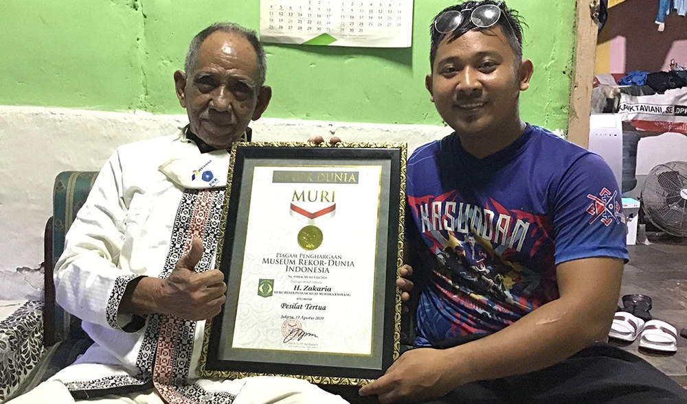 Zakaria Abdurochim and his 26-year-old grandson Alfarisy pose with the certificate declaring him as Indonesia’s oldest Pencak Silat fighter at 91 years old. (Supplied)