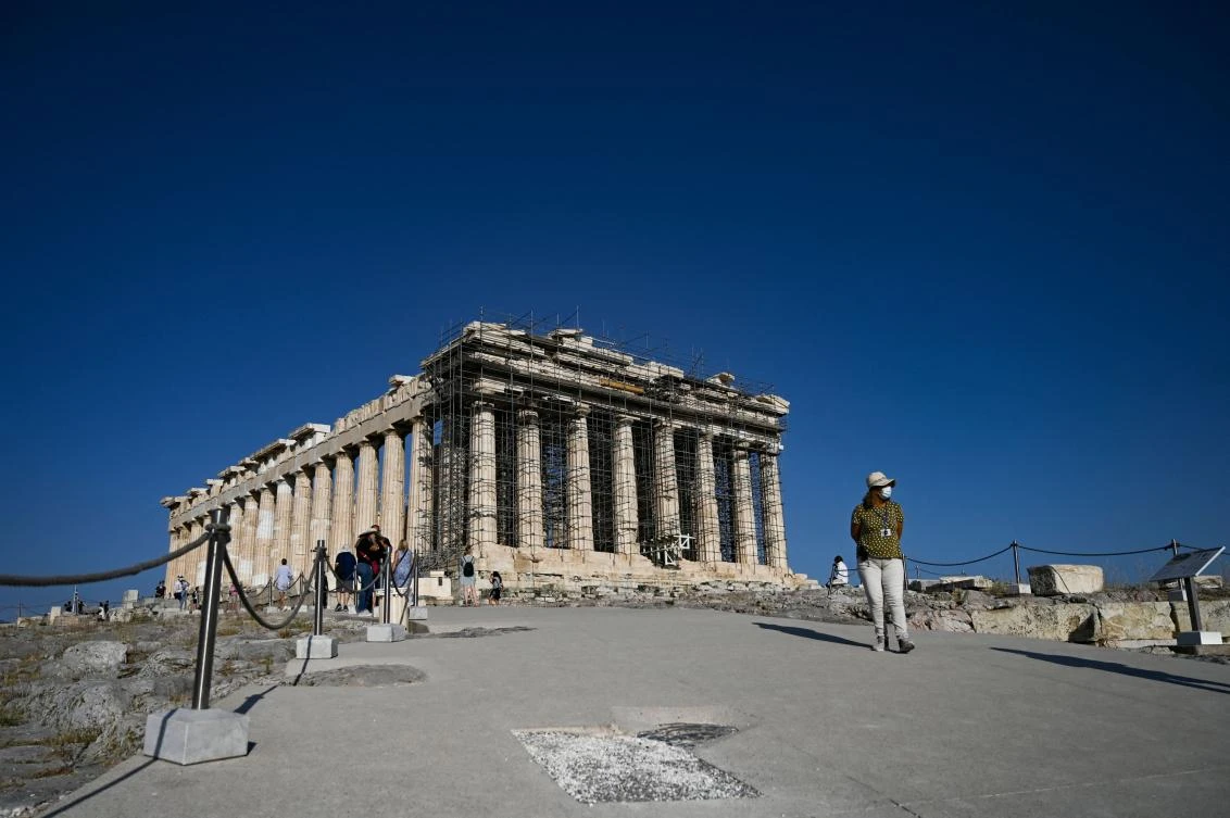 Tourists walk in front of the Ancient temple of Parthenon on the Acropolis hill in Athens. (AFP)