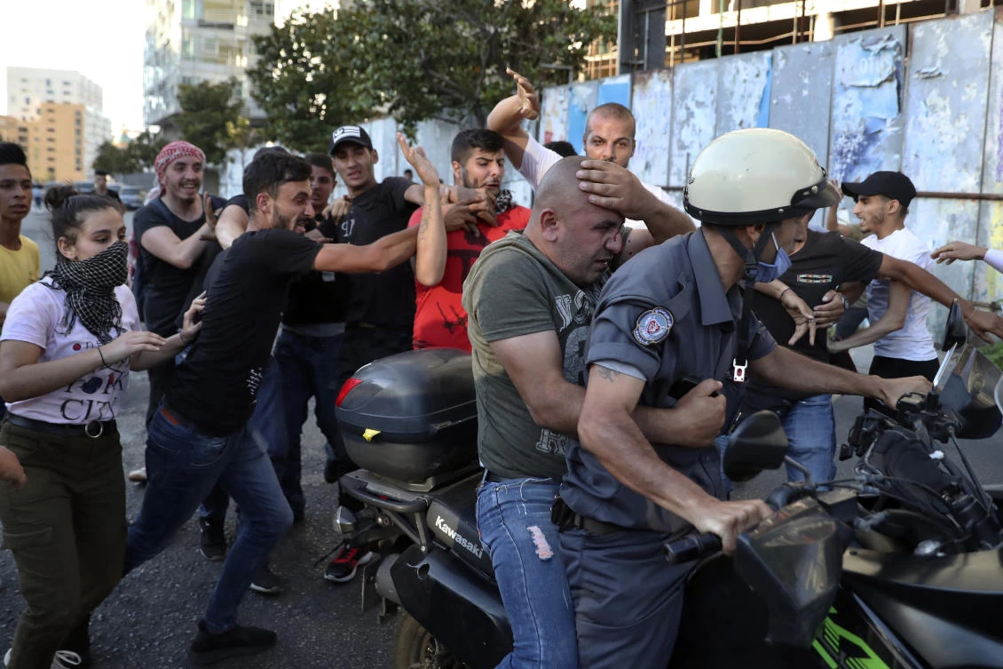 Anti-government protesters hit a member of police intelligence who was taking pictures of protesters, in Beirut. The man fled the scene on the motorcycle of a traffic policeman. (AP)