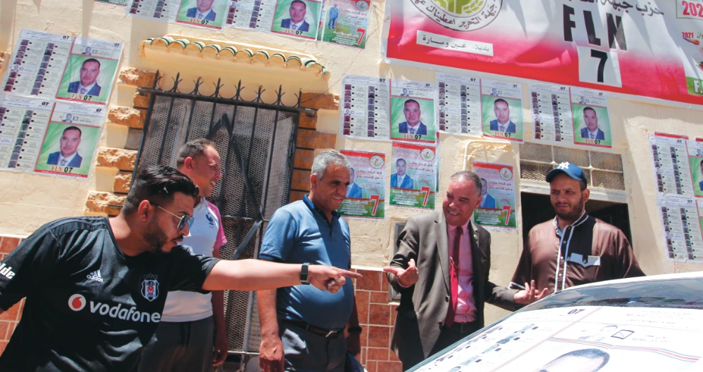 Men argue in front of electoral posters on Thursday in Ain Ouessara. (AP)