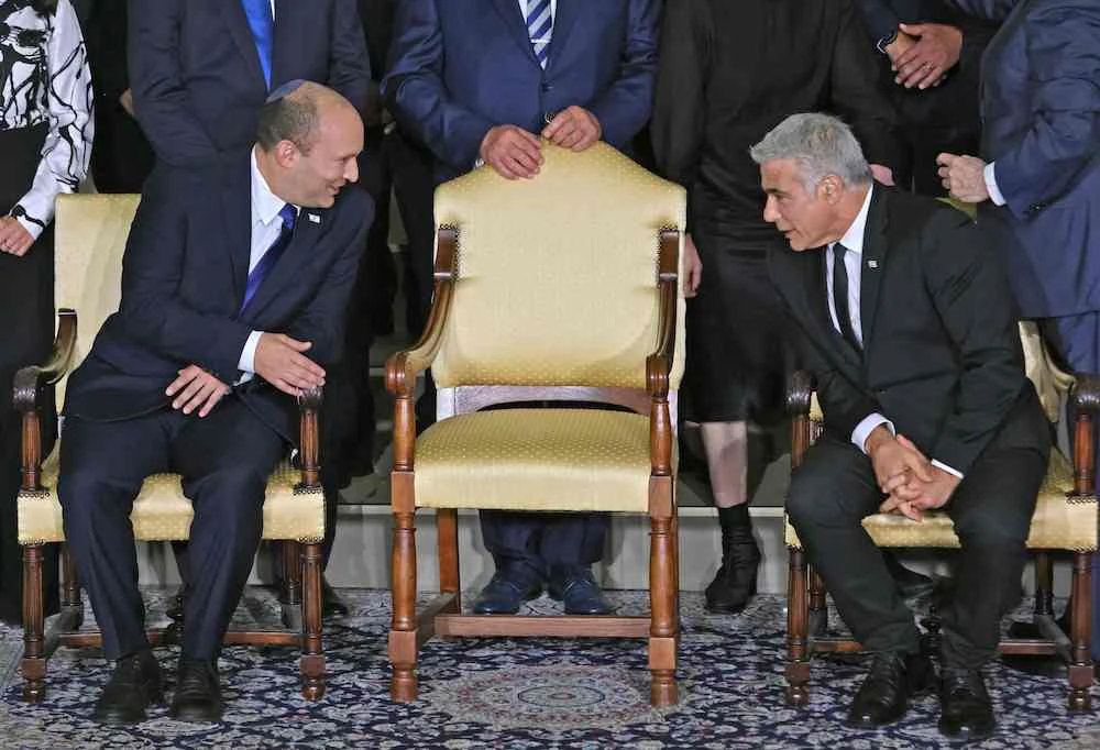 Israeli Prime Minister Naftali Bennett (L) and alternate Prime Minister and Foreign Minister Yair Lapid chat ahead of a photo of the new coalition government. (AFP)