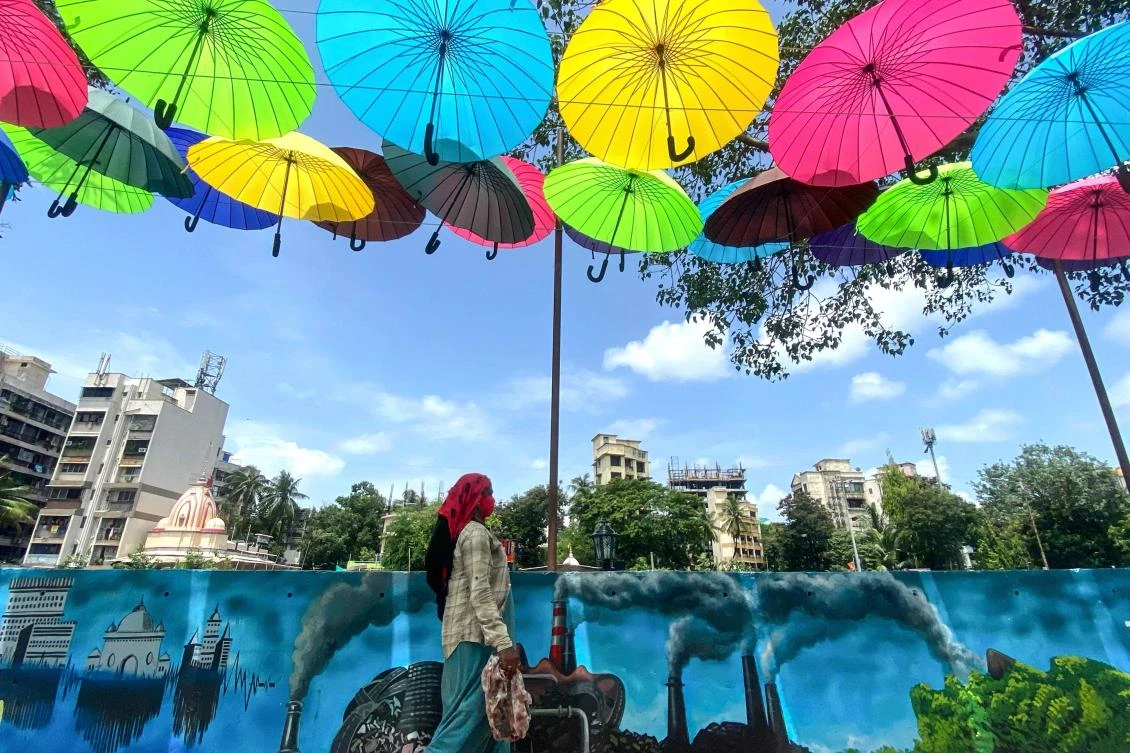 A city civic worker walks under an art installation of colourful umbrellas in Mumbai, India, where shares hit an all time high on Tuesday. (AFP)