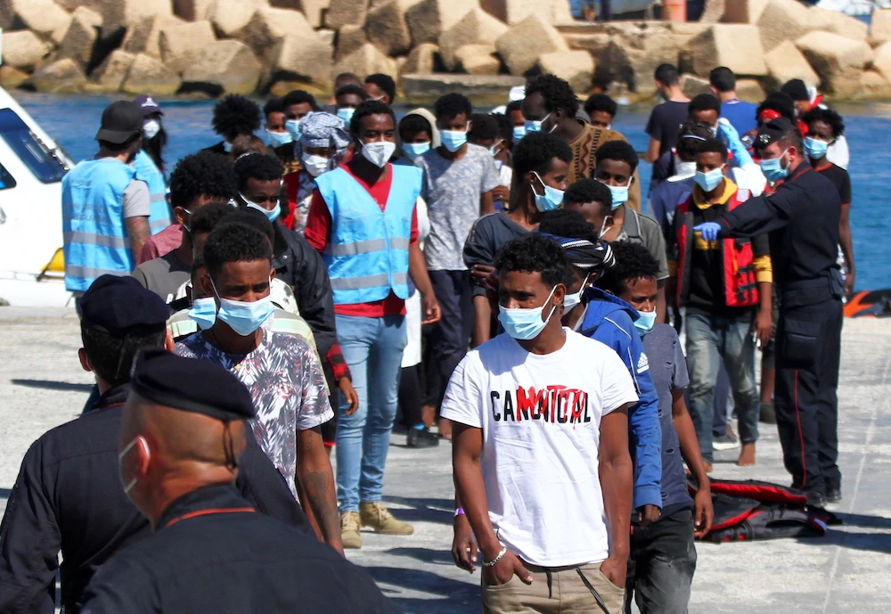 Migrants disembark from a coast guard vessel, after arriving by the hundreds packed on boats, on the southern island of Lampedusa, Italy, May 9, 2021. (Reuters)