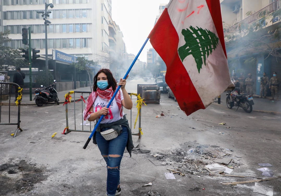 A demonstrator carries a national flag during a protest against mounting economic hardships, near the Central Bank building, in Beirut. (Reuters)
