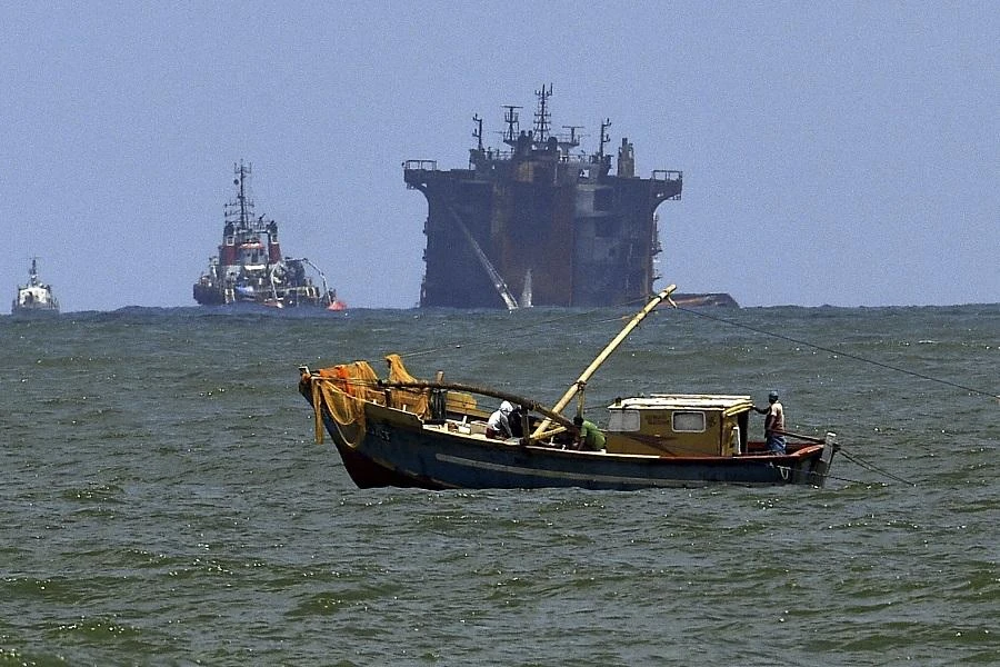 A Sri Lankan fishing boat operates in the backdrop of the site where the Singapore-registered container ship MV X-Press Pearl, which is sinking after burning for almost three weeks in the sea off Colombo Harbour, in Colombo on June 18, 2021. (File/AFP)